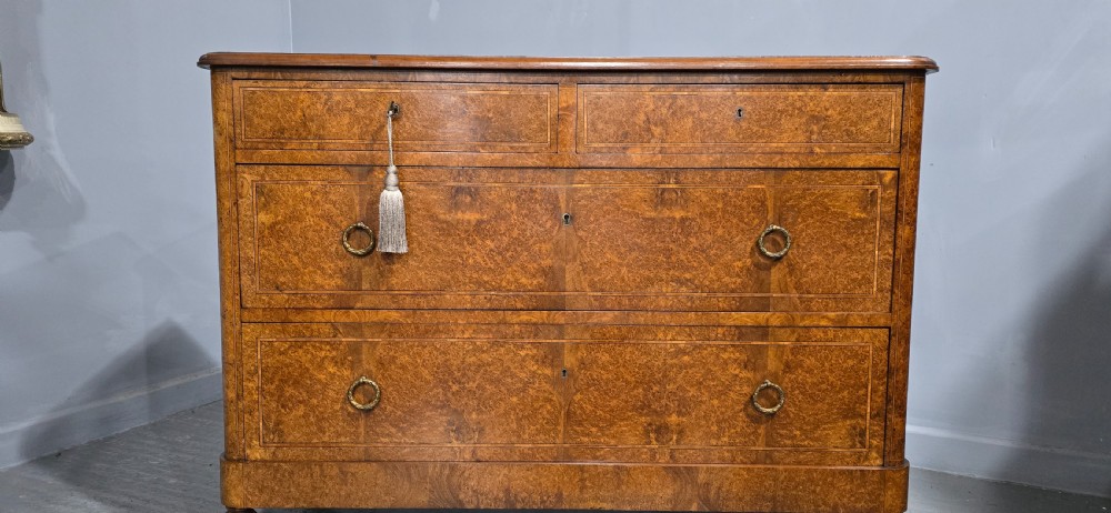 A French amboyna chest of drawers featuring two short drawers over two long drawers, brass ring handles, and turned reeded feet. View III