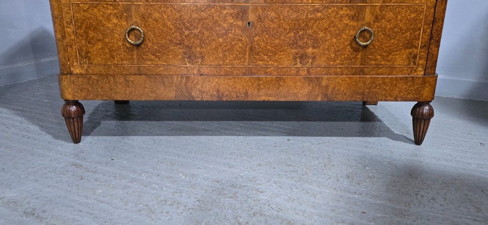 A French amboyna chest of drawers featuring two short drawers over two long drawers, brass ring handles, and turned reeded feet. View IV