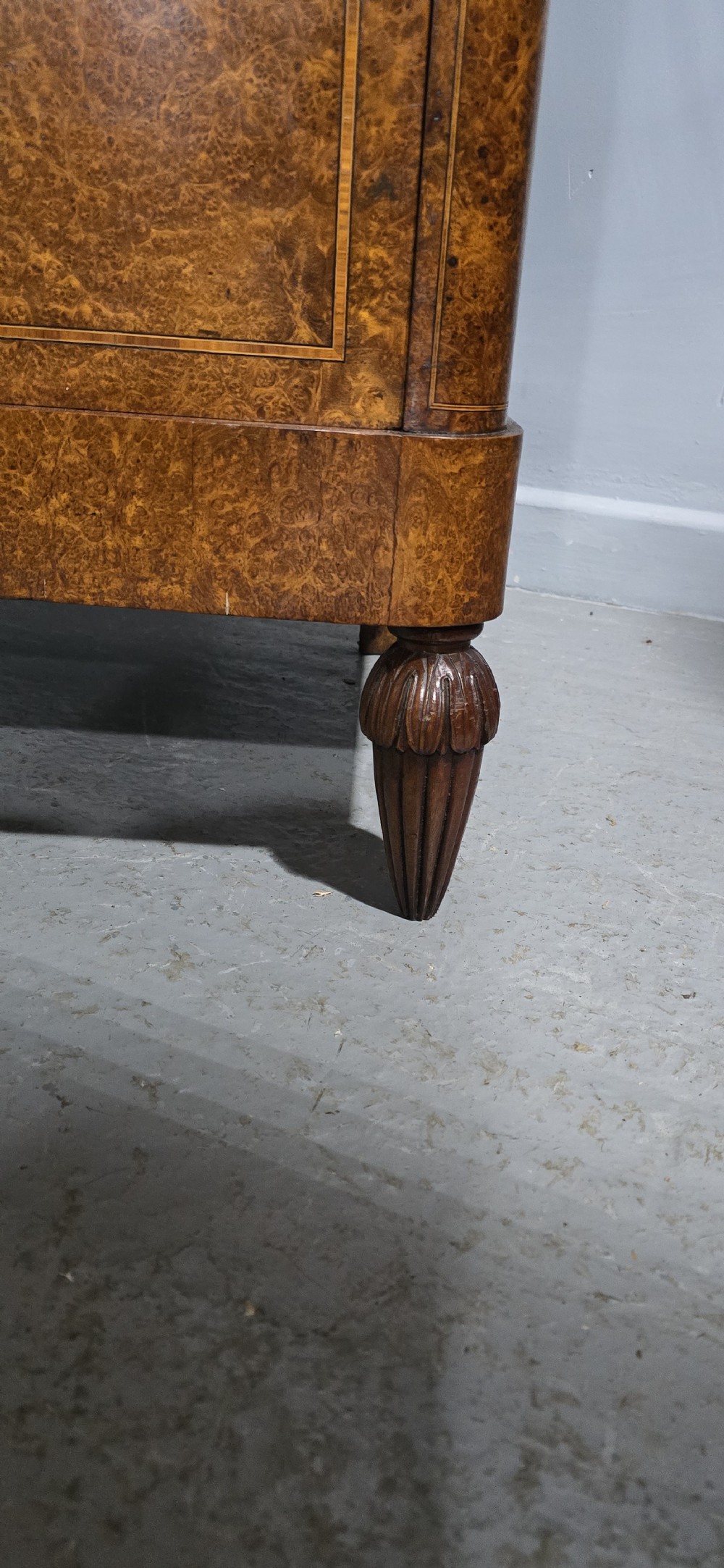A French amboyna chest of drawers featuring two short drawers over two long drawers, brass ring handles, and turned reeded feet. View V
