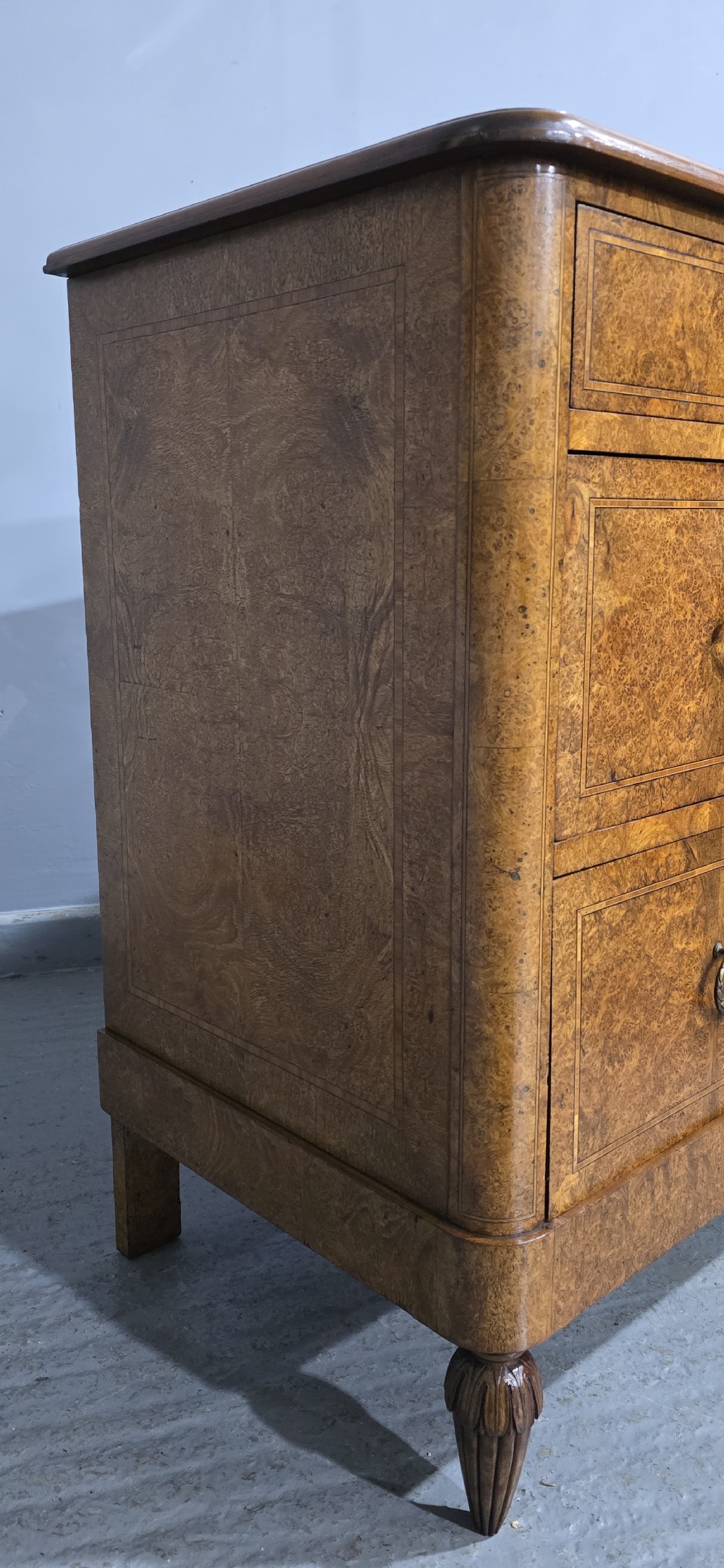 A French amboyna chest of drawers featuring two short drawers over two long drawers, brass ring handles, and turned reeded feet. View VI