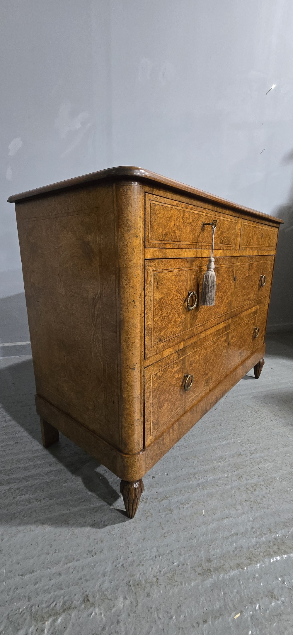 A French amboyna chest of drawers featuring two short drawers over two long drawers, brass ring handles, and turned reeded feet. View VII