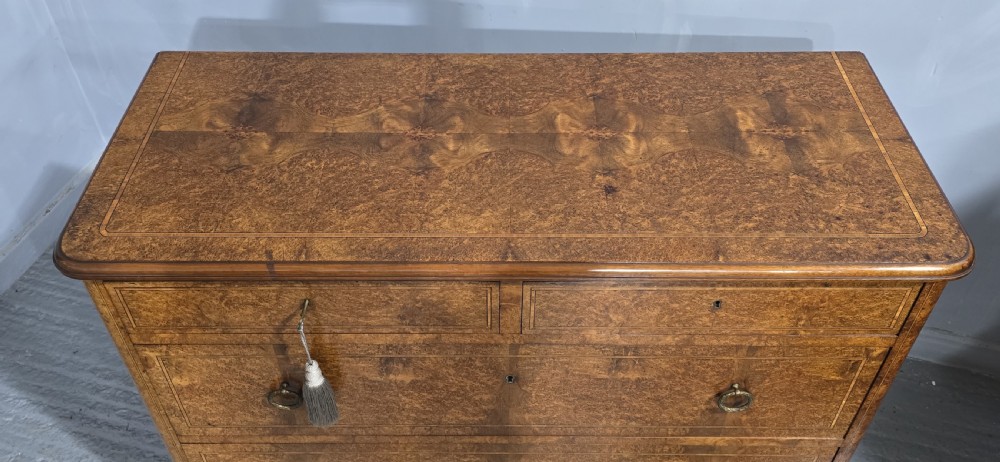A French amboyna chest of drawers featuring two short drawers over two long drawers, brass ring handles, and turned reeded feet. View IX