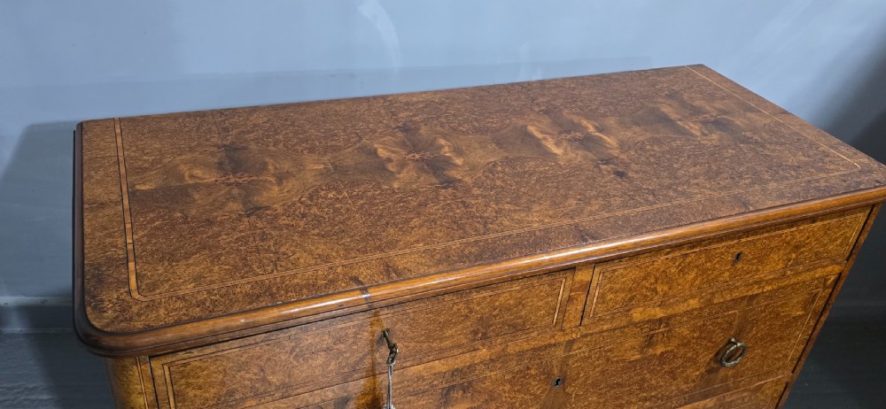 A French amboyna chest of drawers featuring two short drawers over two long drawers, brass ring handles, and turned reeded feet. View XIII