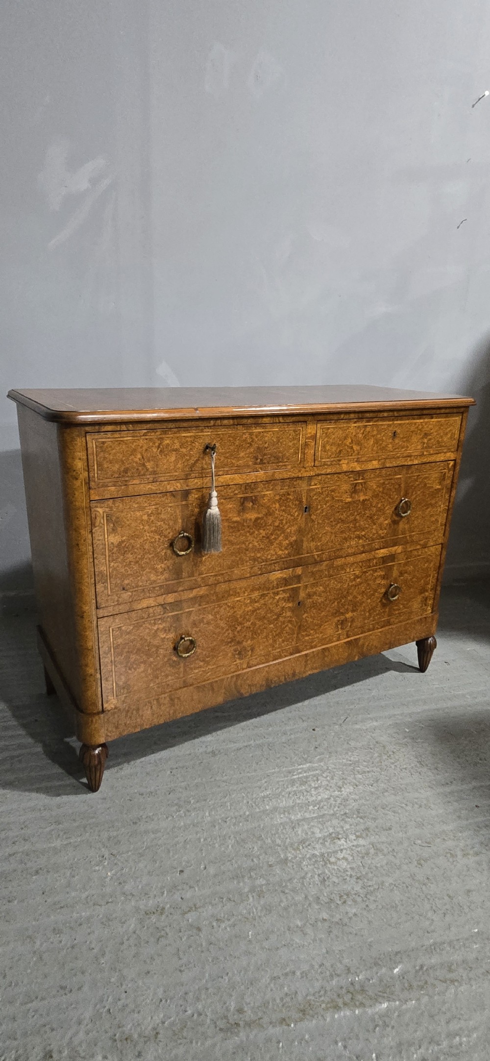 A French amboyna chest of drawers featuring two short drawers over two long drawers, brass ring handles, and turned reeded feet. View XIV