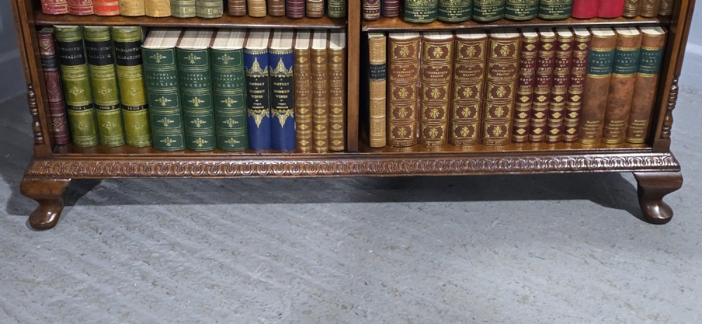 A low warm brown wooden open bookcase featuring four frieze drawers above adjustable shelving sections on carved cabriole feet. View II