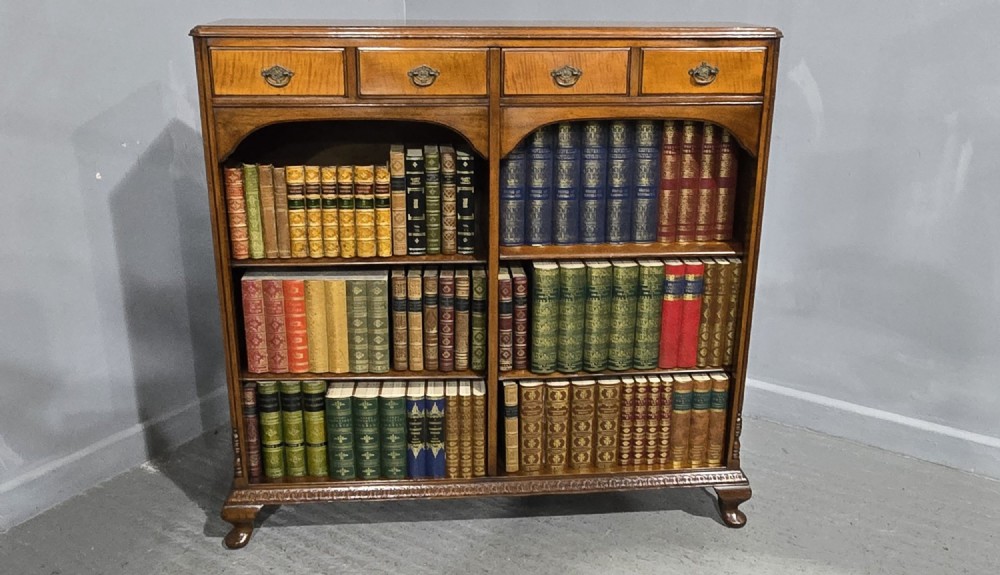A low warm brown wooden open bookcase featuring four frieze drawers above adjustable shelving sections on carved cabriole feet. View III
