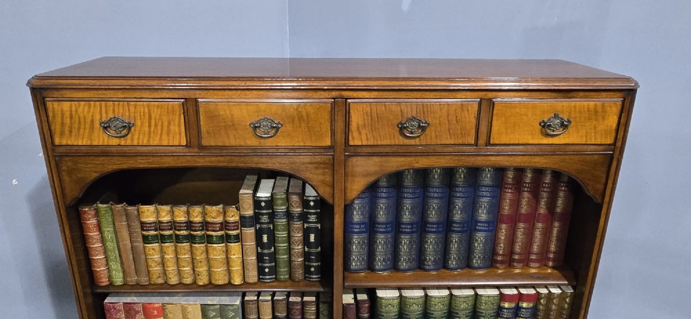 A low warm brown wooden open bookcase featuring four frieze drawers above adjustable shelving sections on carved cabriole feet. View IV