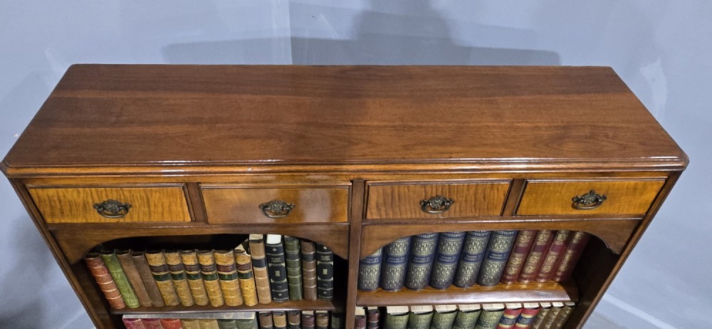 A low warm brown wooden open bookcase featuring four frieze drawers above adjustable shelving sections on carved cabriole feet. View VI