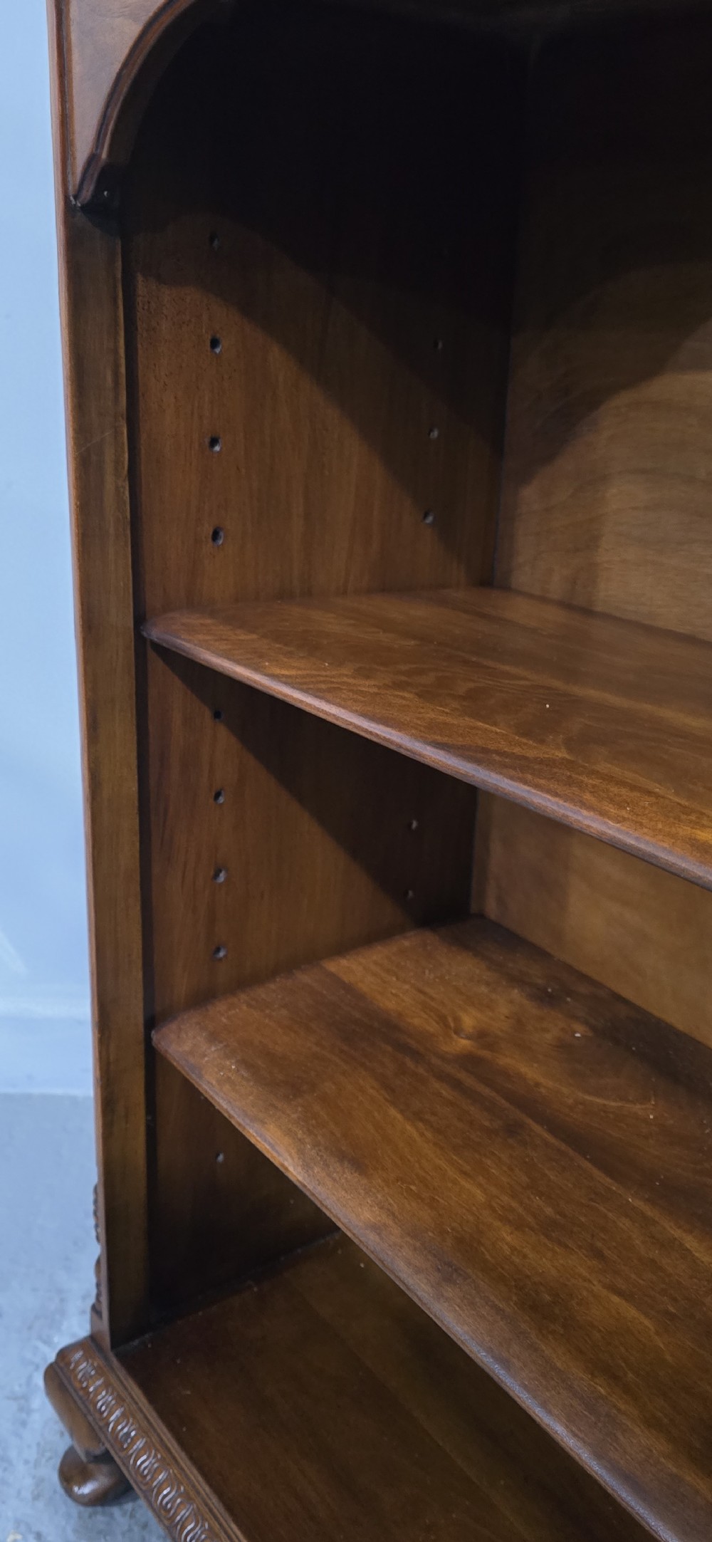 A low warm brown wooden open bookcase featuring four frieze drawers above adjustable shelving sections on carved cabriole feet. View XI