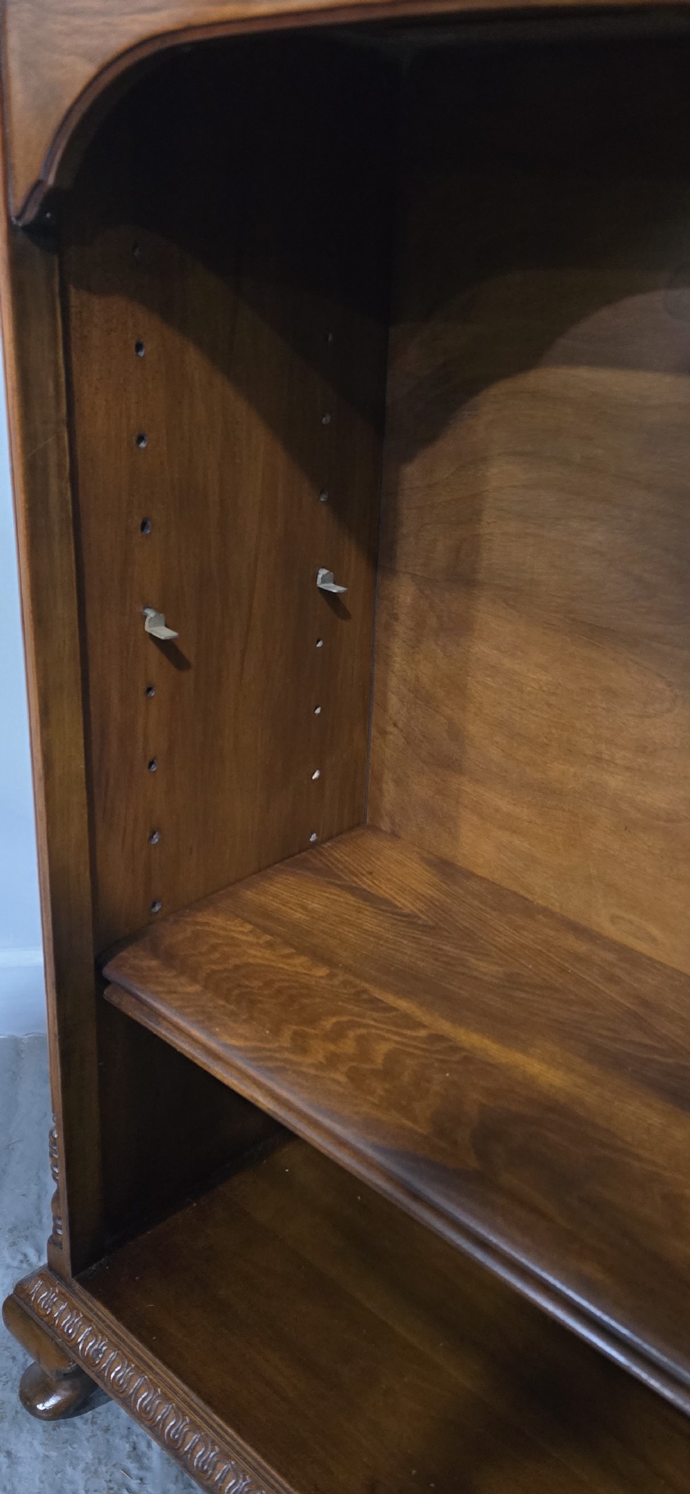 A low warm brown wooden open bookcase featuring four frieze drawers above adjustable shelving sections on carved cabriole feet. View XII