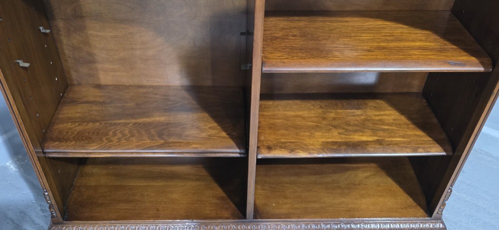 A low warm brown wooden open bookcase featuring four frieze drawers above adjustable shelving sections on carved cabriole feet. View XIII