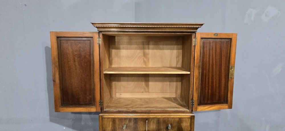A tall mahogany linen press featuring a double-door upper cupboard with flame mahogany panels over four long drawers with turned knobs. View XI