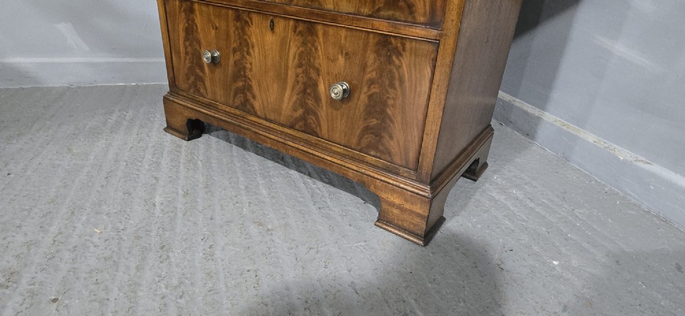 A tall mahogany linen press featuring a double-door upper cupboard with flame mahogany panels over four long drawers with turned knobs. View XII