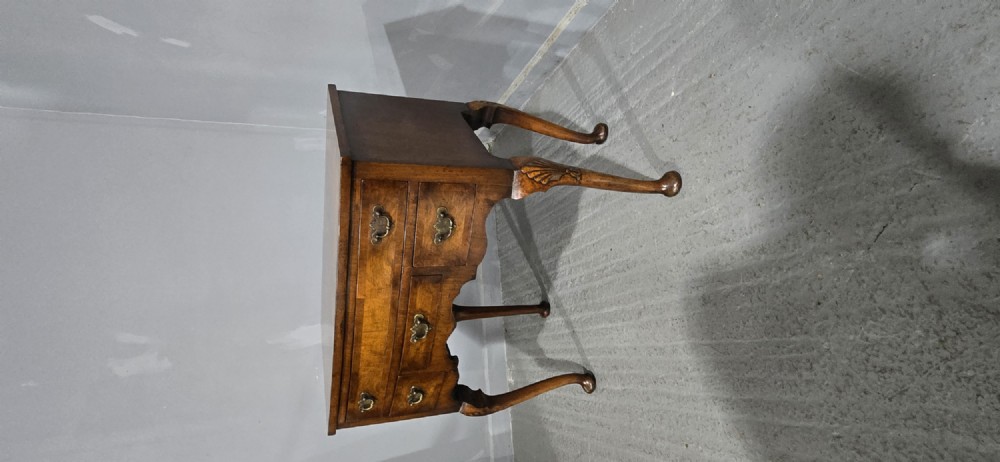 A Queen Anne style burr walnut lowboy table featuring cabriole legs with carved knees, pad feet, brass drop handles, and a shaped apron. View II
