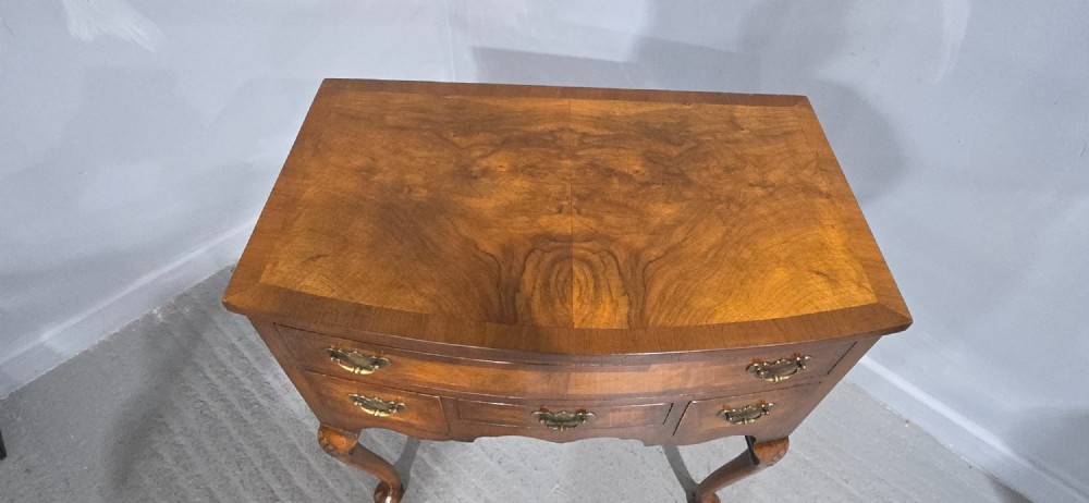 A Queen Anne style burr walnut lowboy table featuring cabriole legs with carved knees, pad feet, brass drop handles, and a shaped apron. View VI