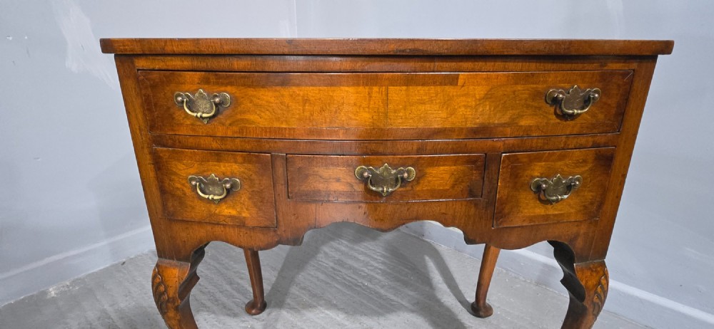 A Queen Anne style burr walnut lowboy table featuring cabriole legs with carved knees, pad feet, brass drop handles, and a shaped apron. View VIII