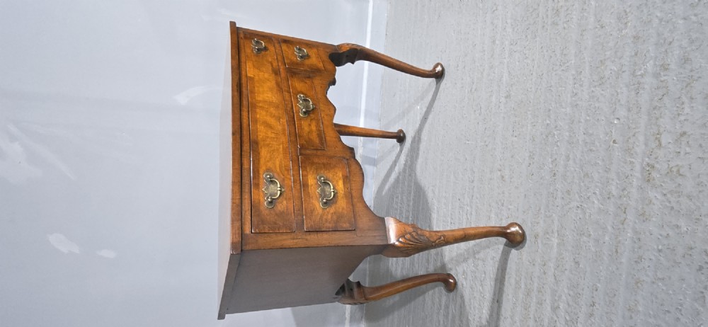 A Queen Anne style burr walnut lowboy table featuring cabriole legs with carved knees, pad feet, brass drop handles, and a shaped apron. View IX