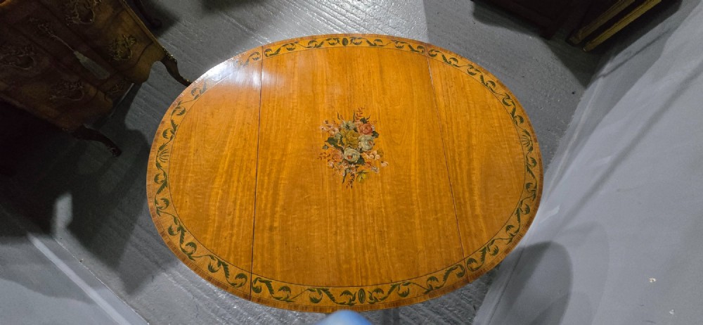 An antique painted satinwood Pembroke table featuring two drop leaves, hand-painted floral borders, turned tapering legs, and a single frieze drawer. View V