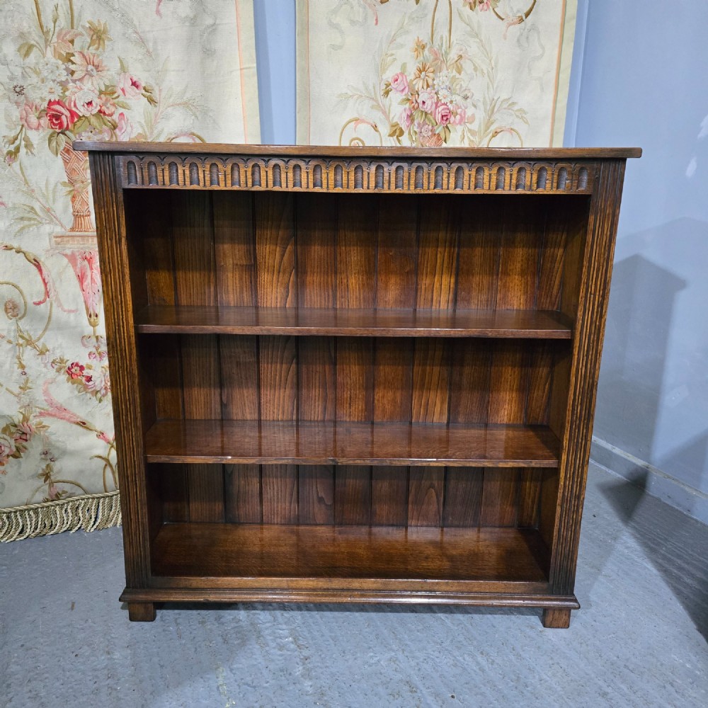 A low solid oak open bookcase with three shelves filled with antiquarian books, featuring a carved arcaded frieze and reeded side moulding. View II