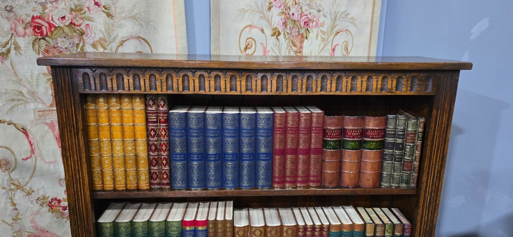 A low solid oak open bookcase with three shelves filled with antiquarian books, featuring a carved arcaded frieze and reeded side moulding. View III