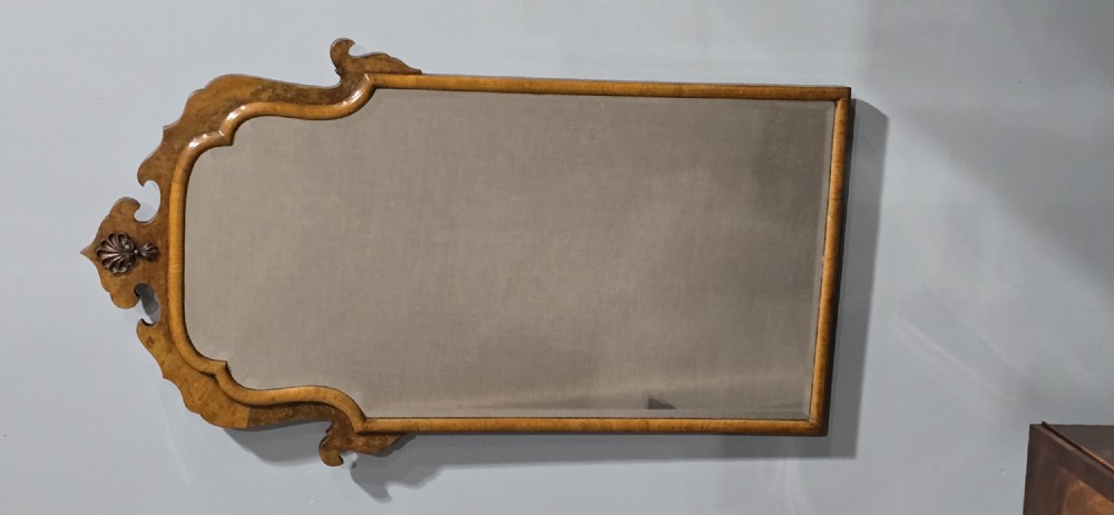 A vertical Queen Anne style wall mirror framed in burr walnut with an arched top and carved shell cresting. View III