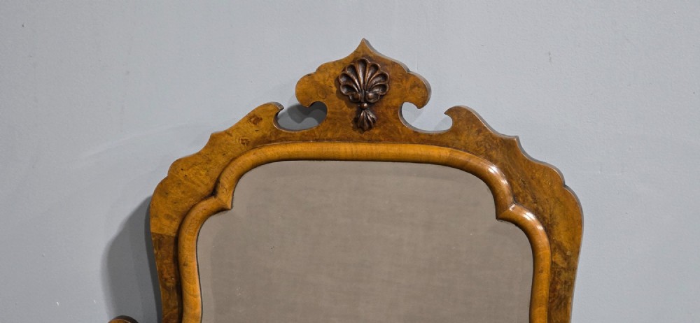 A vertical Queen Anne style wall mirror framed in burr walnut with an arched top and carved shell cresting. View IV