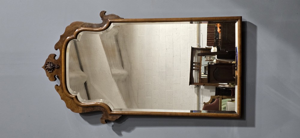 A vertical Queen Anne style wall mirror framed in burr walnut with an arched top and carved shell cresting. View VIII