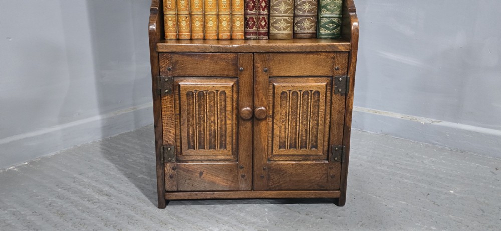 A dark solid oak open bookcase featuring three upper shelves and a two-door base cupboard with carved vertical panels. View VI