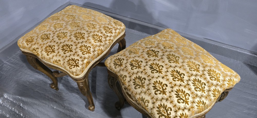 A pair of French giltwood stools featuring patterned gold velvet upholstery, carved cabriole legs, and ornate stretchers. View II