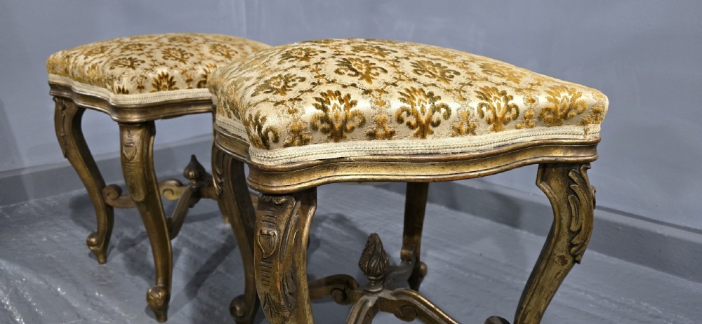 A pair of French giltwood stools featuring patterned gold velvet upholstery, carved cabriole legs, and ornate stretchers. View VII