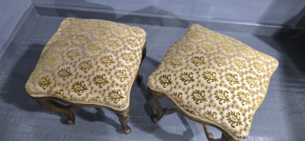 A pair of French giltwood stools featuring patterned gold velvet upholstery, carved cabriole legs, and ornate stretchers. View VIII