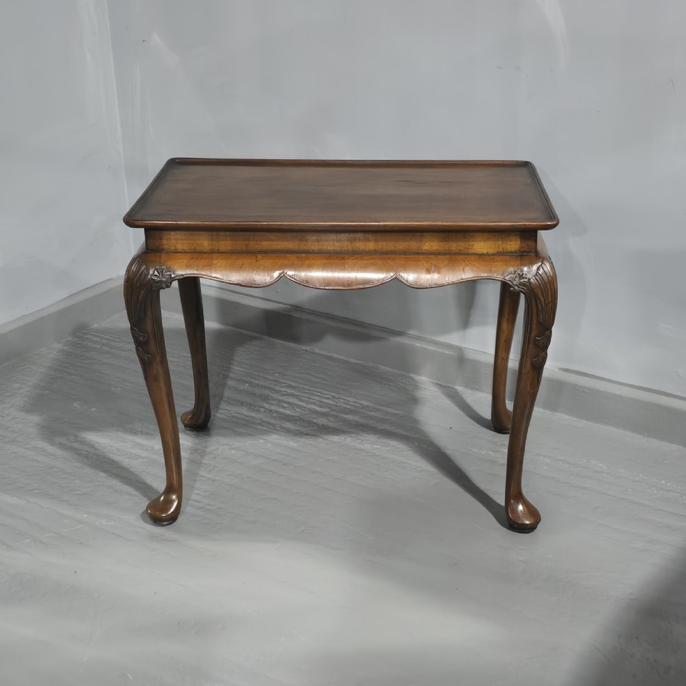A rectangular walnut tray-top table with a moulded lip rim, a scalloped frieze, and carved cabriole legs.