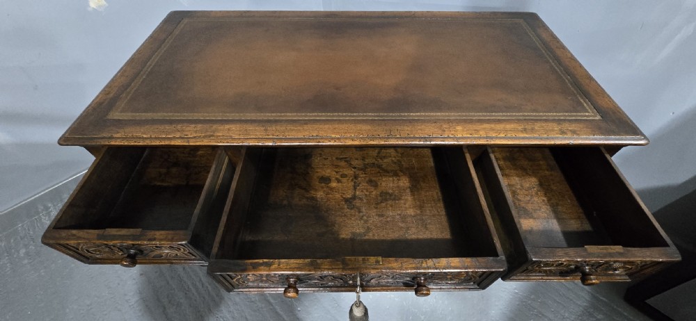 An antique dark oak pedestal desk featuring carved floral frieze drawers, turned wooden knobs, and two pedestals with three drawers each. View VI