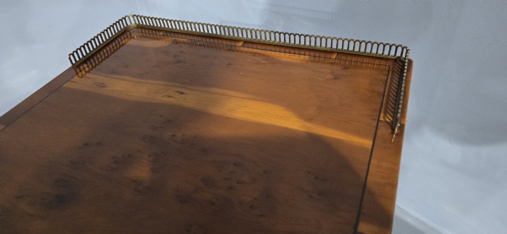 A two-tiered yew wood lamp table featuring a brass gallery top rail, turned legs, a lower drawer, and brass castors. View VI