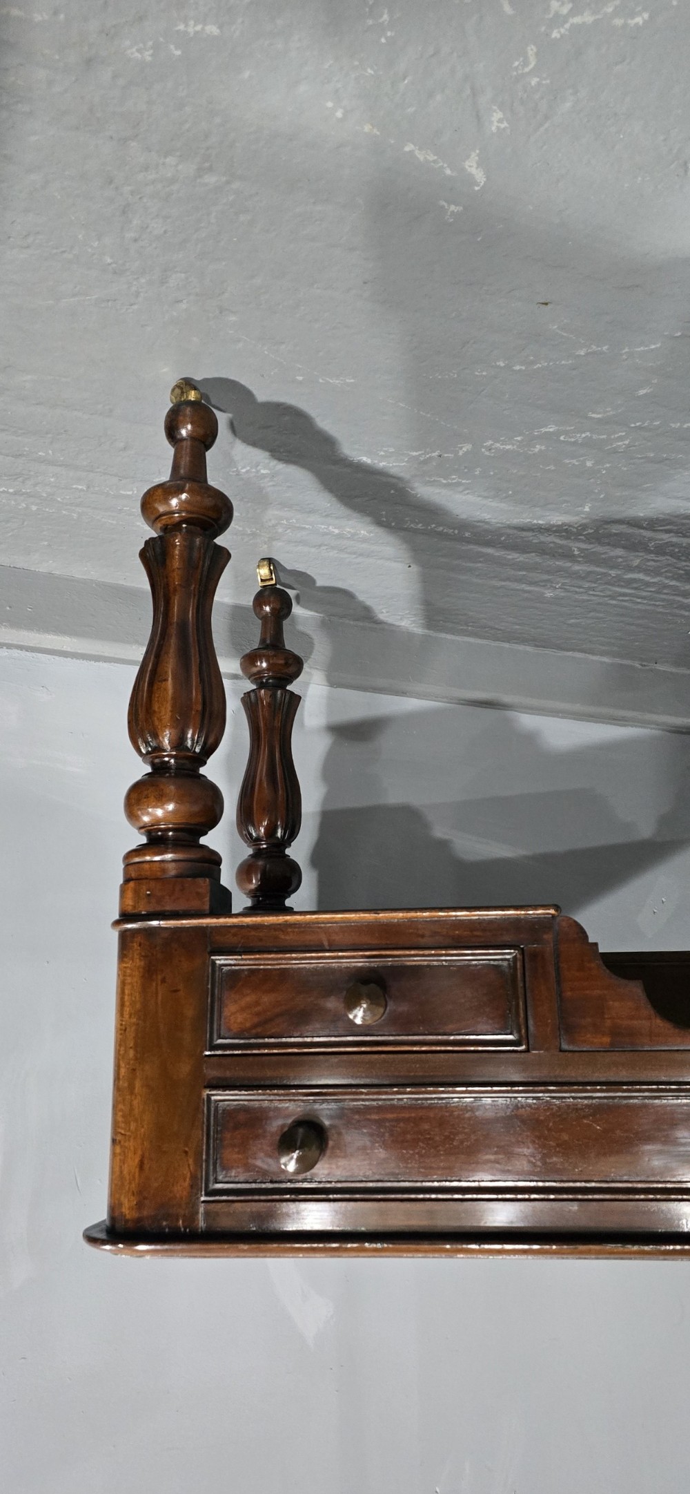 A William IV freestanding mahogany desk featuring a leather writing surface, five drawers with wooden knob handles, and turned legs on brass castors. View III