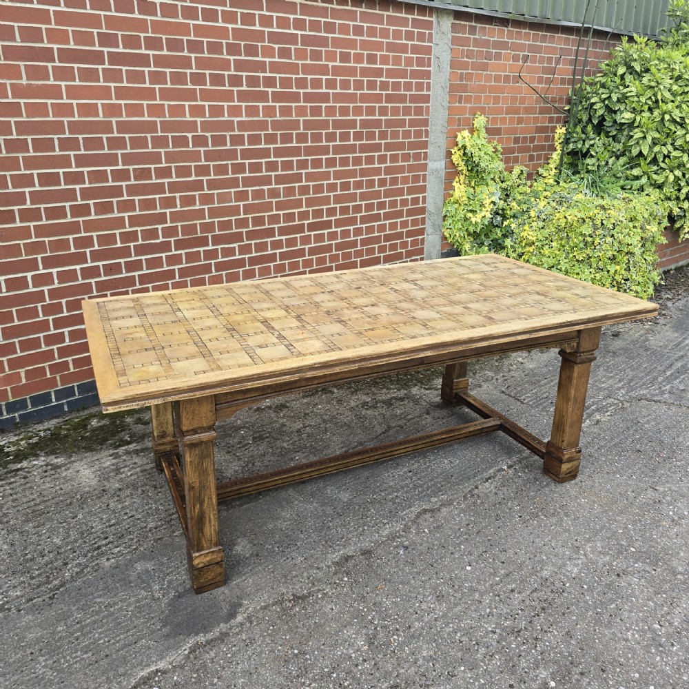 A large rectangular French refectory dining table featuring a patterned parquet timber top, square block legs, and a low stretcher base.