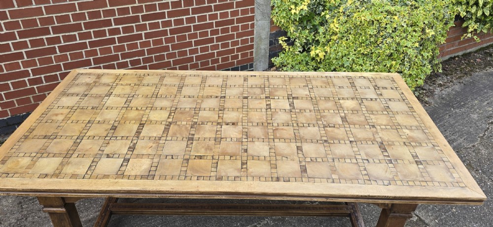 A large rectangular French refectory dining table featuring a patterned parquet timber top, square block legs, and a low stretcher base. View VI