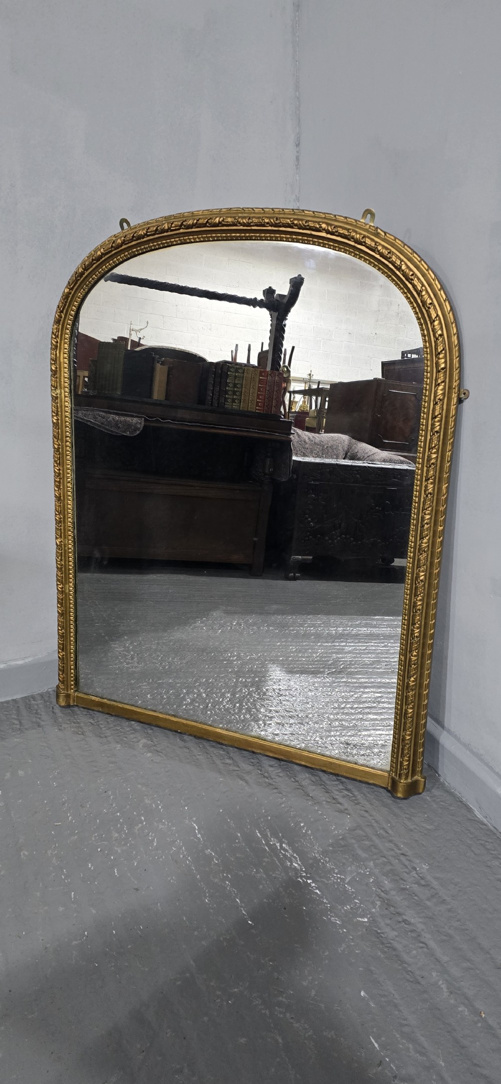 A Victorian arched overmantel mirror with an ornate gilded frame featuring detailed beaded moulding and a flat base. View II