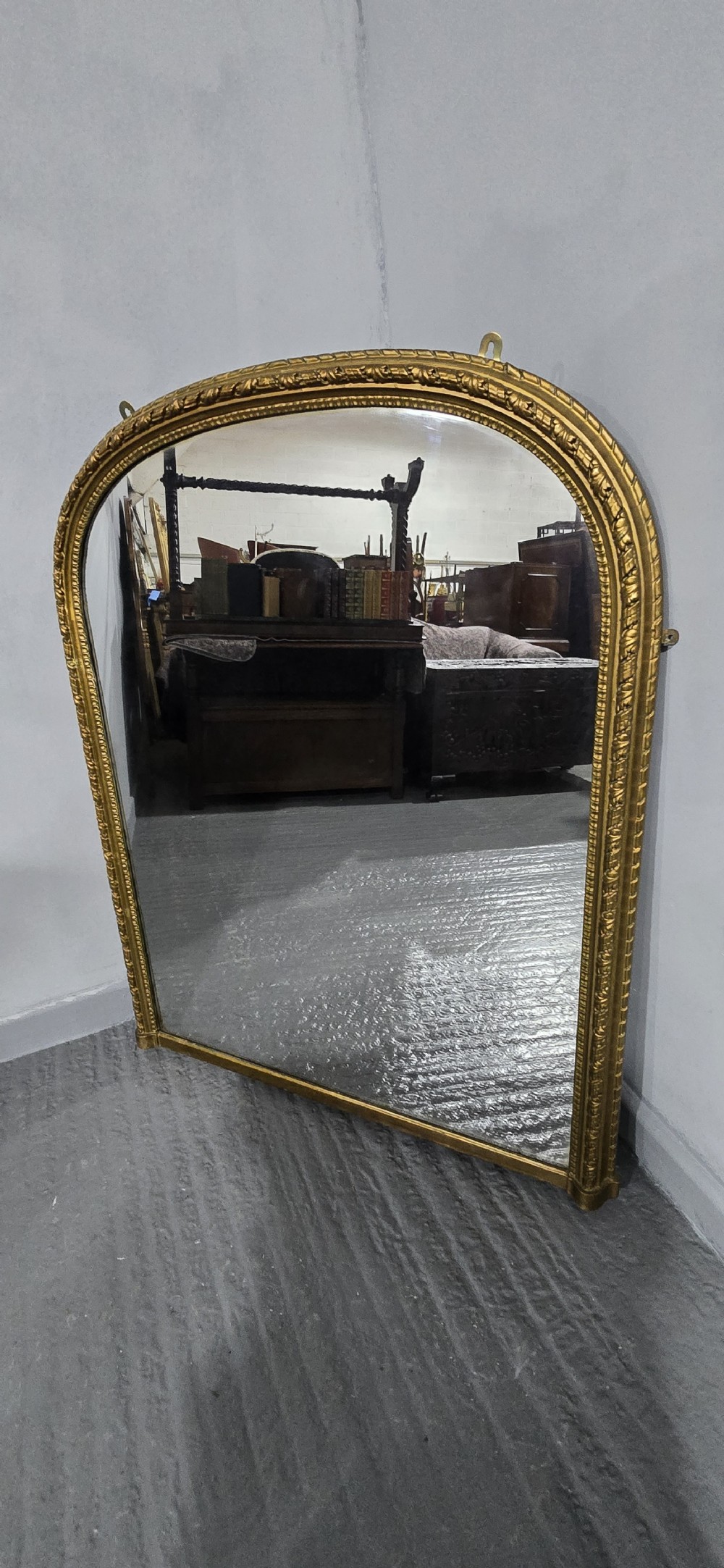 A Victorian arched overmantel mirror with an ornate gilded frame featuring detailed beaded moulding and a flat base. View VII