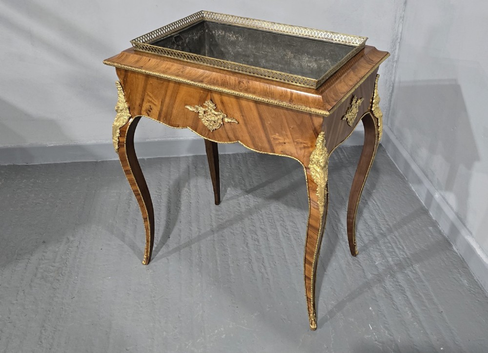 A Louis XV style satinwood jardiniere table featuring quartered wood veneer, ornate gilded bronze mounts, cabriole legs, a pierced brass gallery, and a metal liner. View VI