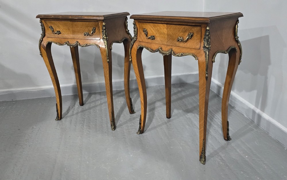 A pair of French Rococo style bedside tables with marquetry tops, single drawers, and ornate brass mounts on cabriole legs. View IV
