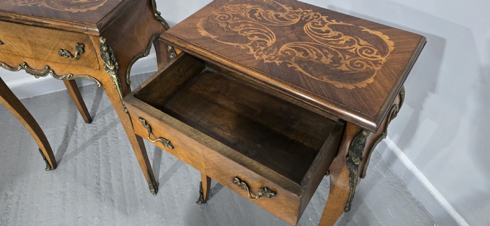A pair of French Rococo style bedside tables with marquetry tops, single drawers, and ornate brass mounts on cabriole legs. View IX