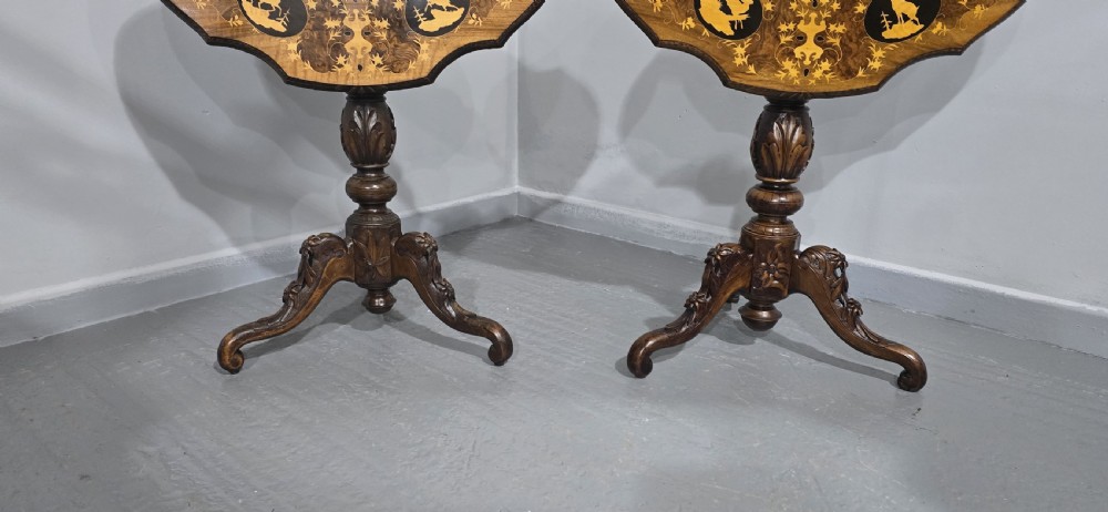 A pair of antique Black Forest carved walnut side tables featuring intricate marquetry tops with animal silhouettes on tripod pedestal bases. View II