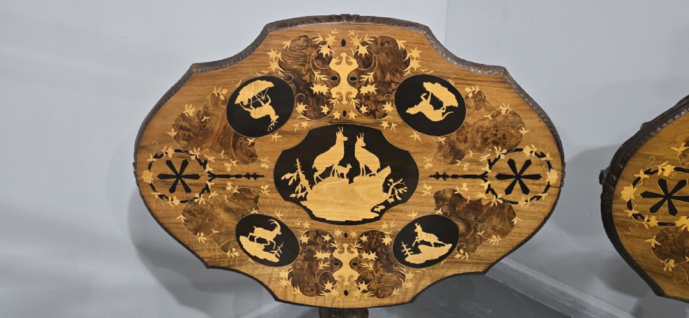 A pair of antique Black Forest carved walnut side tables featuring intricate marquetry tops with animal silhouettes on tripod pedestal bases. View III