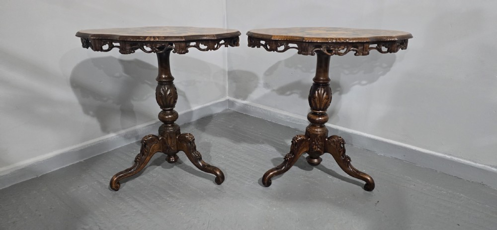 A pair of antique Black Forest carved walnut side tables featuring intricate marquetry tops with animal silhouettes on tripod pedestal bases. View V