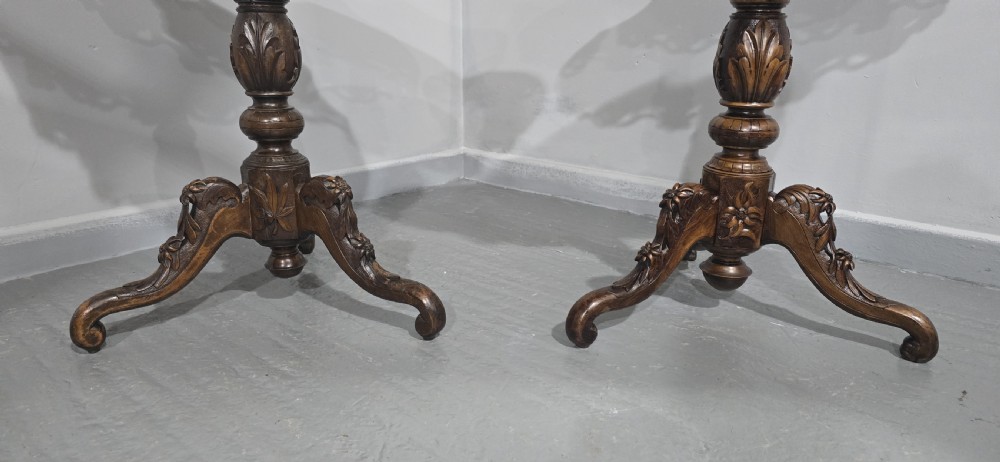 A pair of antique Black Forest carved walnut side tables featuring intricate marquetry tops with animal silhouettes on tripod pedestal bases. View VI