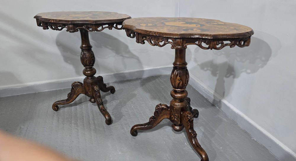 A pair of antique Black Forest carved walnut side tables featuring intricate marquetry tops with animal silhouettes on tripod pedestal bases. View IX
