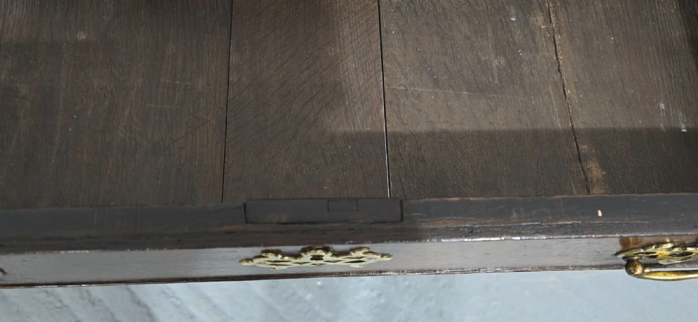 A dark oak 17th-century lowboy featuring three drawers with brass drop handles and a shaped kneehole apron set on straight square legs. View XI