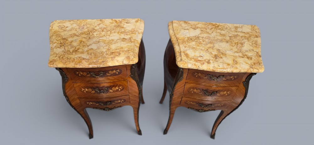 A pair of French Louis XV style bedside tables featuring floral marquetry drawers, gilt bronze mounts, and variegated marble tops. View V