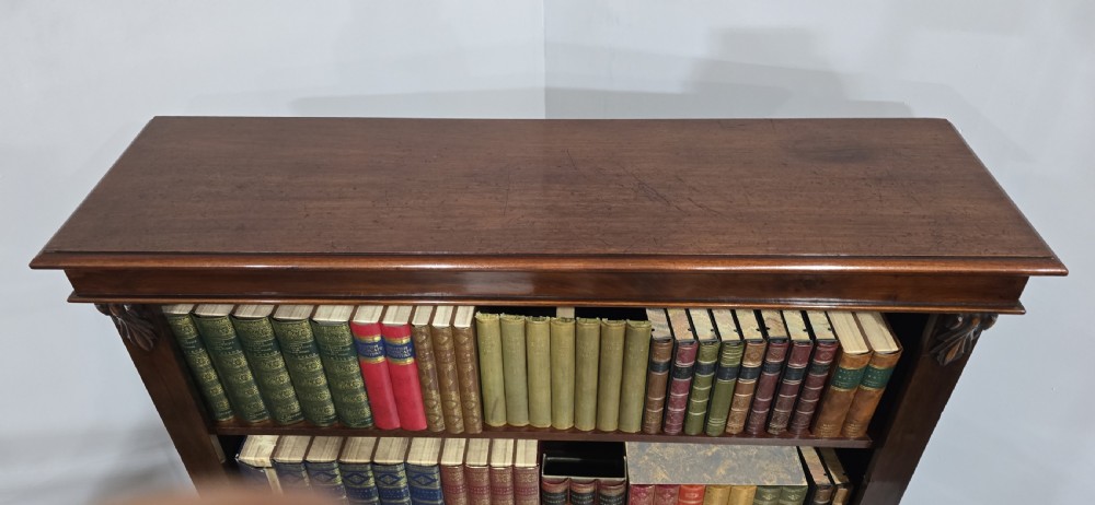 A Victorian mahogany open bookcase featuring three adjustable shelves filled with leather-bound books, flanked by carved corbels. View V